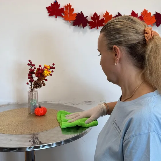 Eine Mitarbeiterin wischt einen Tisch mit einem grünen Tuch ab